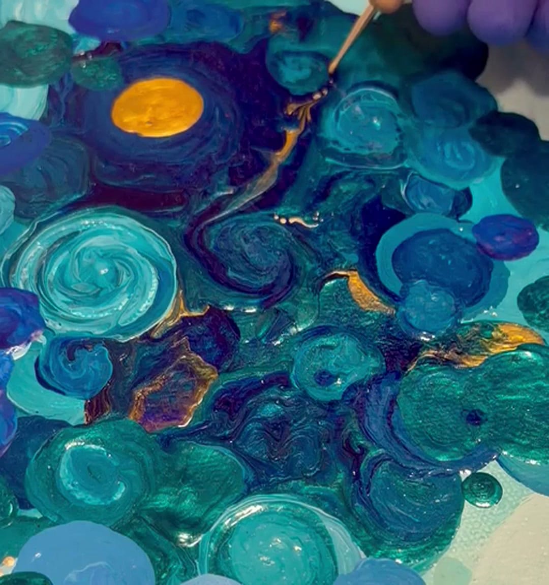 Closeup of wet acrylic in cobalt, turquoise, and amber, with a central gold disc