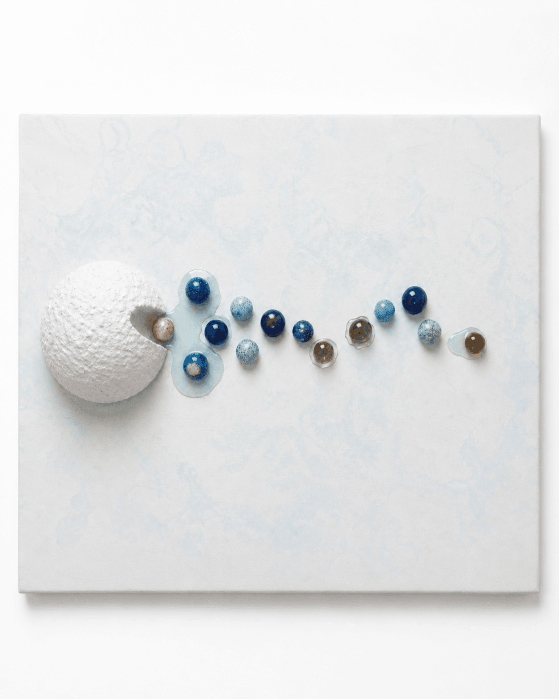 Origin / Release I by Victoria Zeder — large white resin sphere with line of small colored spheres extending across a pale cream field