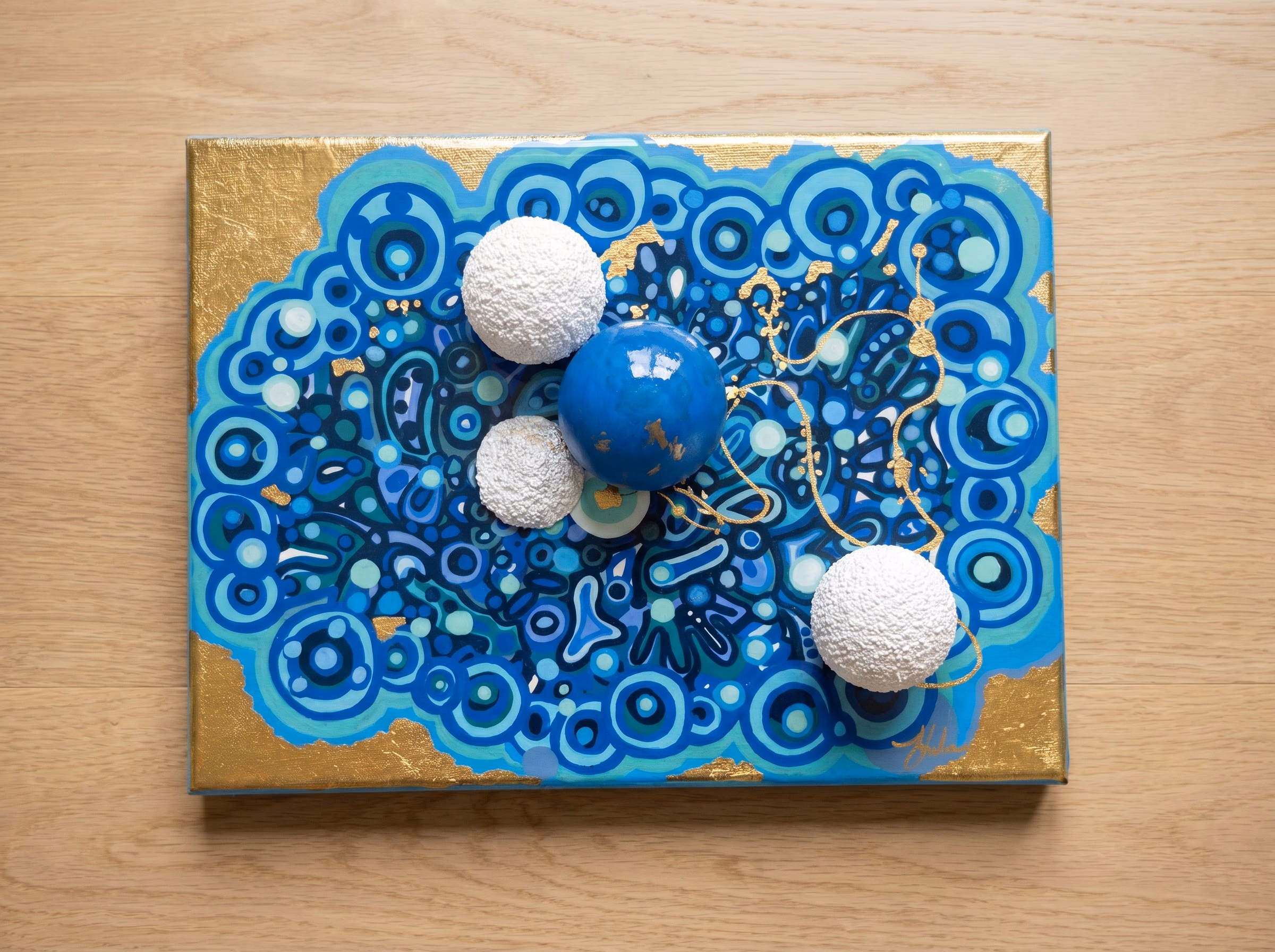 Genesis by Victoria Zeder: small dense field of hand-carved spheres bound by gold filament under resin, 24k gold leaf border